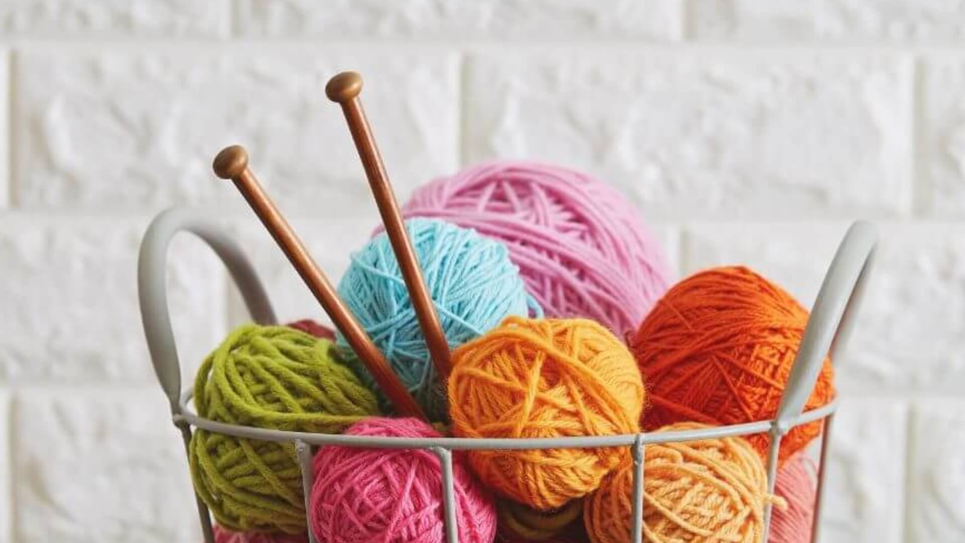 Stricknadeln und bunte Wolle in einem Korb